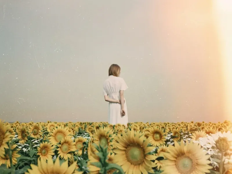 Faded 90s disposable camera photo of a woman in a white dress standing in a sunflower field, with film grain, scratches, motion blur, and warm sunset glow leaking from a corner