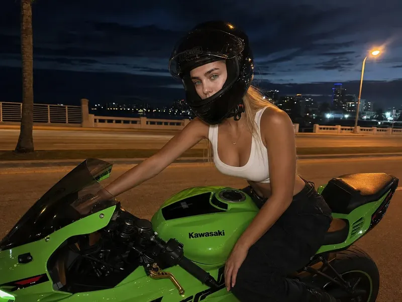 Photorealistic cinematic night street photo of a woman on a bright green Kawasaki-style sport motorcycle wearing a fitted tank top and partially open black helmet, with soft orange streetlight reflections under dusk twilight