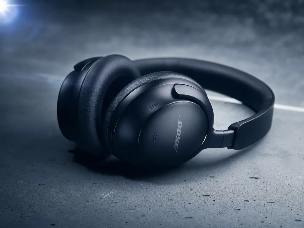 Wireless headphones resting on a minimalist concrete surface under moody blue-tinted studio lighting with a subtle lens flare, low-angle premium product shot