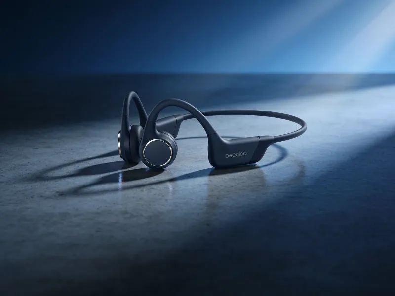 Wireless headphones resting on a minimalist concrete surface under moody blue-tinted studio lighting with a subtle lens flare, low-angle premium product shot