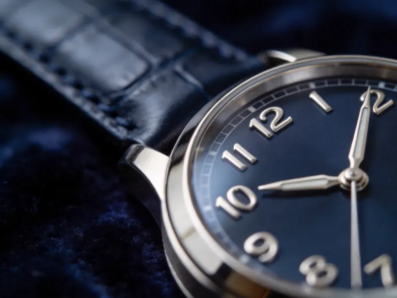 Macro close-up of a watch on a dark navy velvet surface, sharp focus on the dial and indices, soft falloff into the strap, luxury editorial product photography