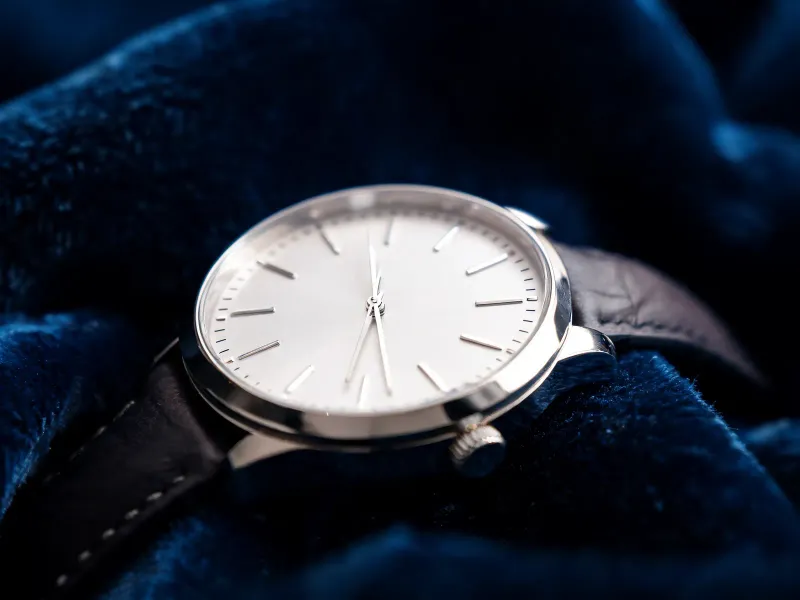Macro close-up of a watch on a dark navy velvet surface, sharp focus on the dial and indices, soft falloff into the strap, luxury editorial product photography
